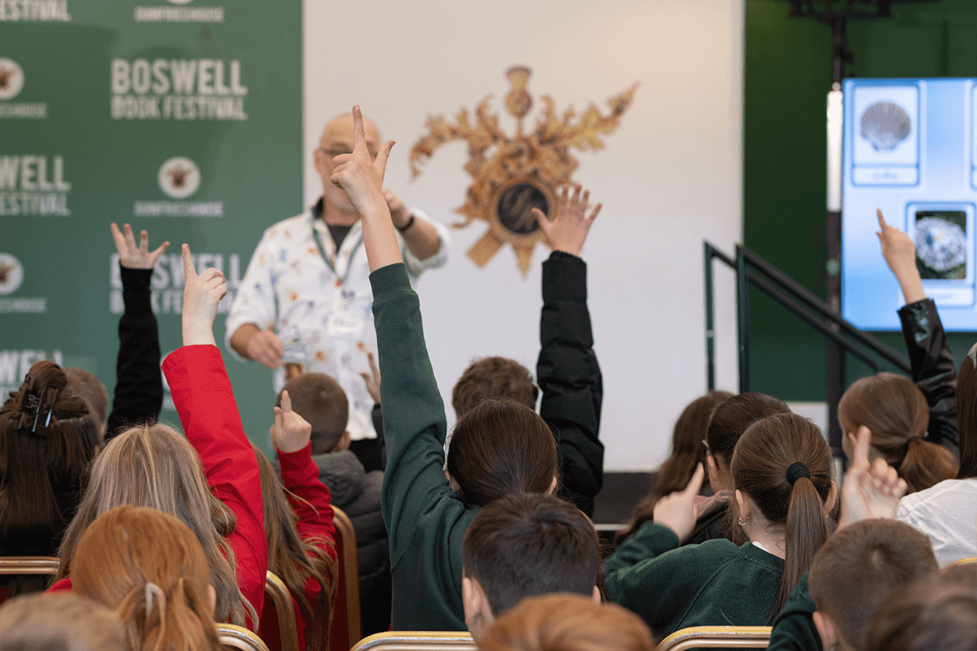 School children with hands raised during a Boswell Book Festival event